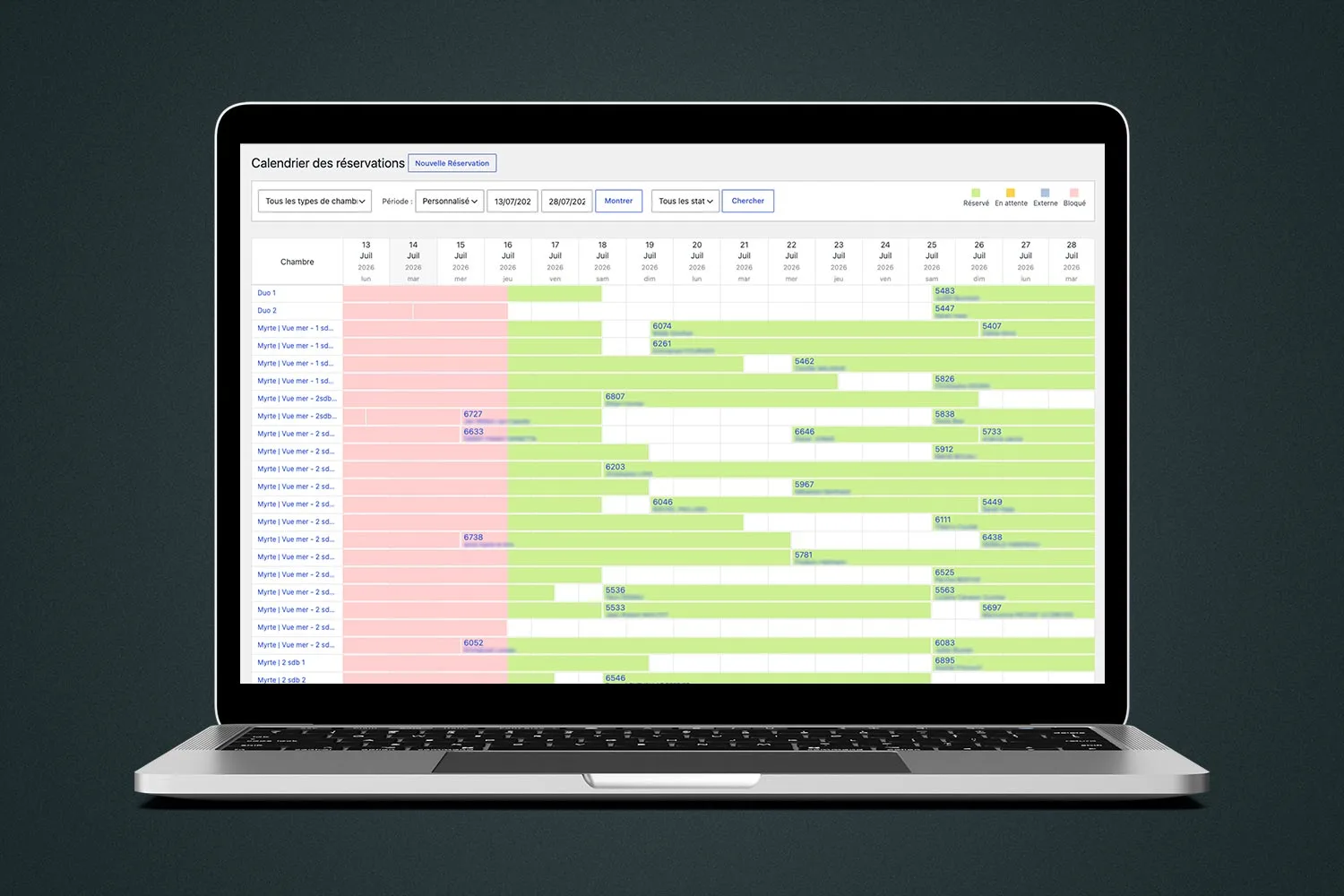 Un ordinateur portable ouvert présente un calendrier de réservations hôtelières en ligne sur fond vert sombre
